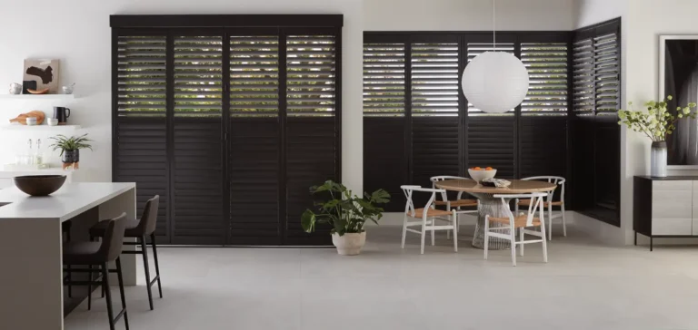 Heritance bi-fold track hardwood shutters over kitchen doors and windows with top open and bottom closed